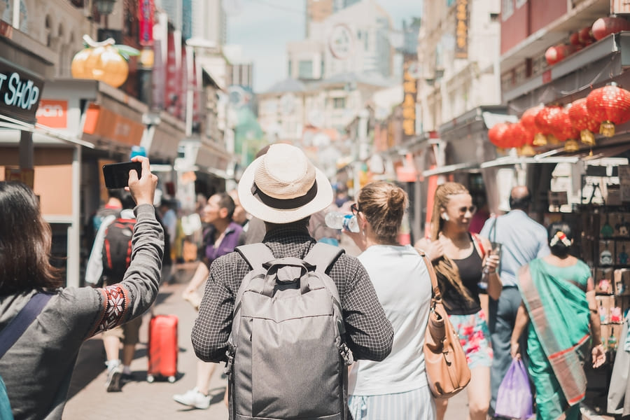 Viajero de espaldas usando sombrero y mochila viendo una calle en china